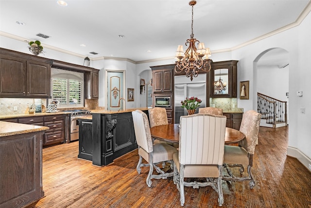 dining room featuring ornamental molding, hardwood / wood-style floors, and an inviting chandelier