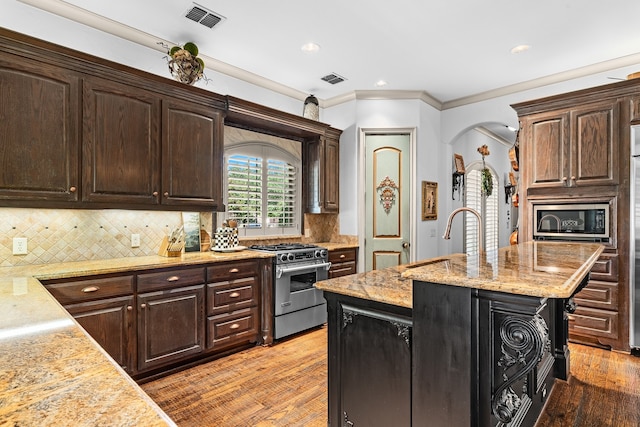 kitchen featuring a kitchen island with sink, light wood-type flooring, dark brown cabinetry, sink, and gas stove