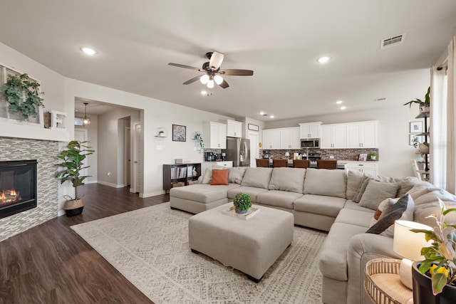 living room featuring hardwood / wood-style flooring, a stone fireplace, and ceiling fan