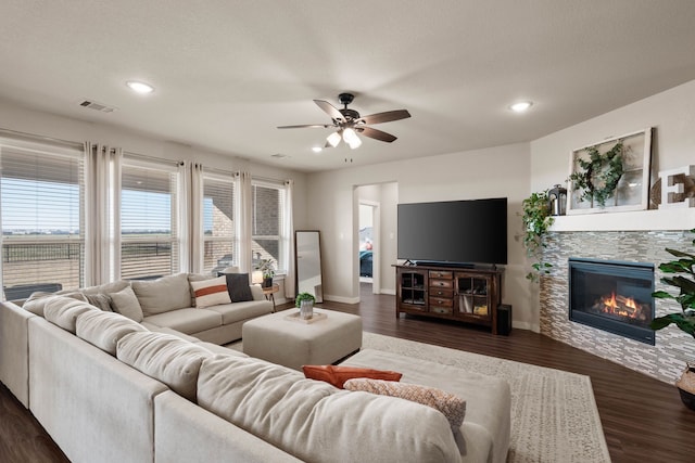 living room featuring a textured ceiling, a fireplace, dark hardwood / wood-style floors, and ceiling fan