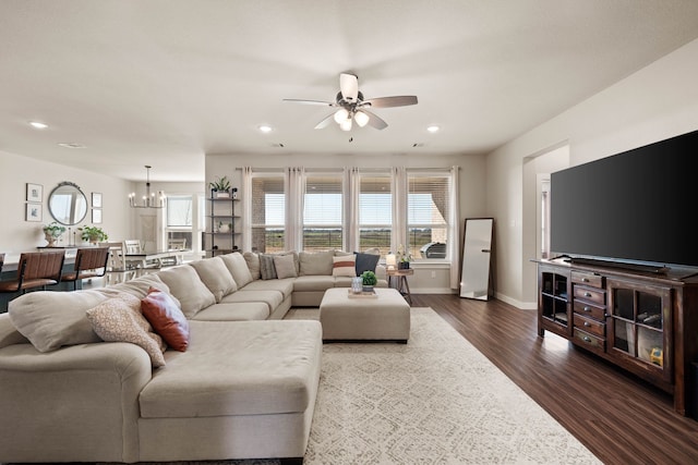 living room featuring dark wood-type flooring and ceiling fan with notable chandelier