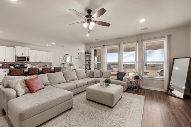 living room featuring a wealth of natural light, wood-type flooring, and ceiling fan with notable chandelier