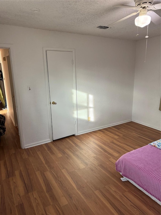 unfurnished bedroom with ceiling fan, hardwood / wood-style floors, and a textured ceiling