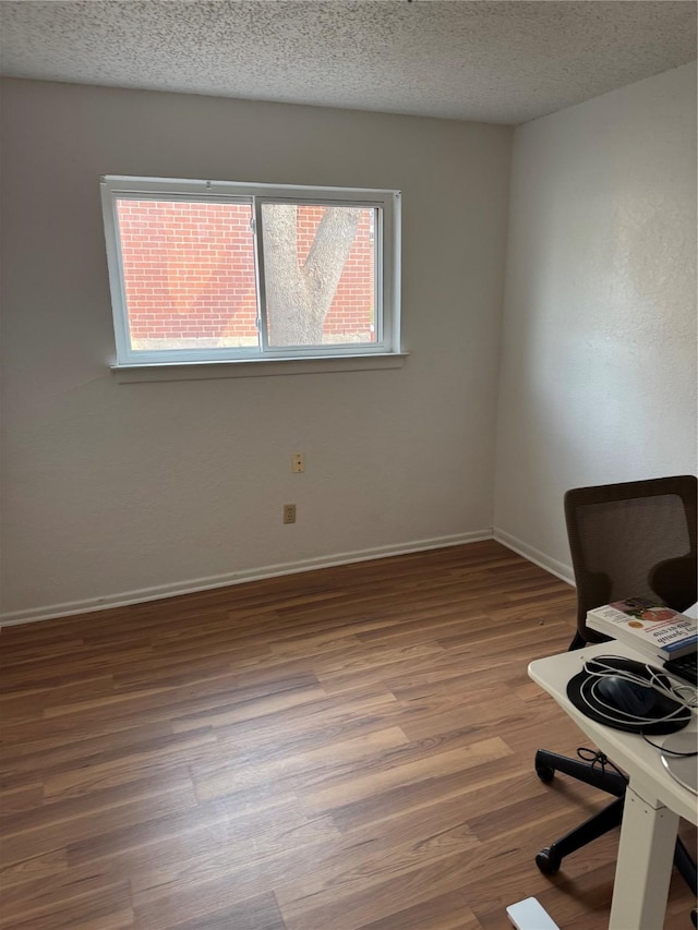 unfurnished office featuring wood-type flooring and a textured ceiling