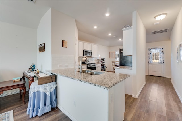 kitchen featuring white cabinets, appliances with stainless steel finishes, sink, kitchen peninsula, and light stone counters