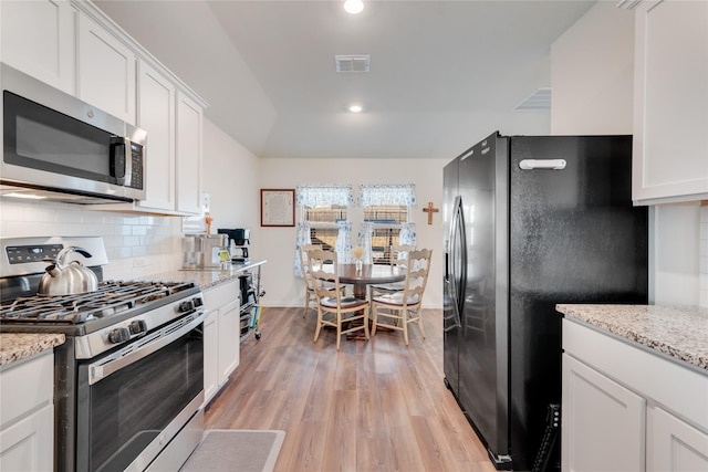 kitchen featuring white cabinets, light hardwood / wood-style floors, light stone counters, and appliances with stainless steel finishes