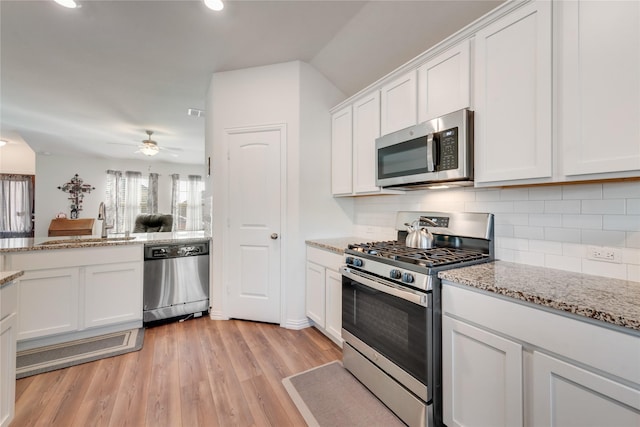 kitchen with appliances with stainless steel finishes, white cabinetry, decorative backsplash, sink, and light wood-type flooring