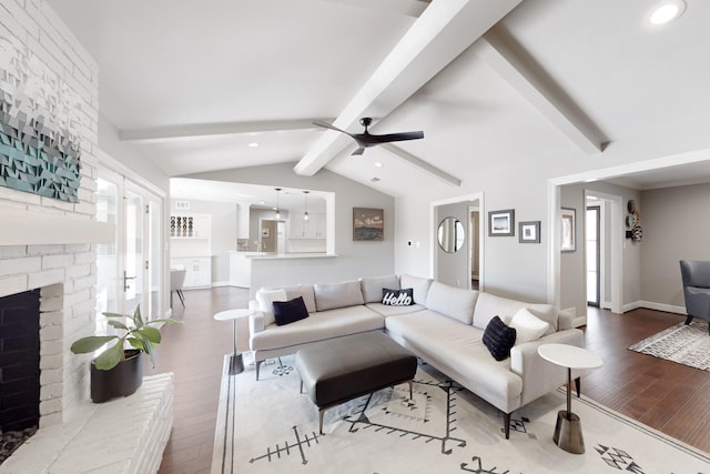 living room featuring hardwood / wood-style flooring, a fireplace, lofted ceiling with beams, and ceiling fan