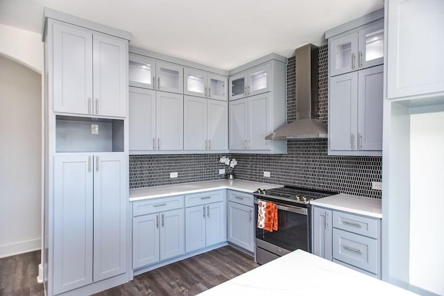 kitchen featuring stainless steel electric stove, wall chimney range hood, decorative backsplash, and dark hardwood / wood-style floors