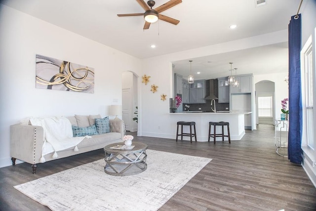 living room featuring ceiling fan, sink, and dark hardwood / wood-style floors