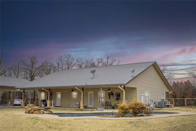 back house at dusk with ceiling fan, a patio, and central AC