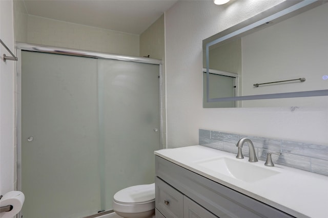 bathroom featuring vanity, toilet, and a shower with shower door