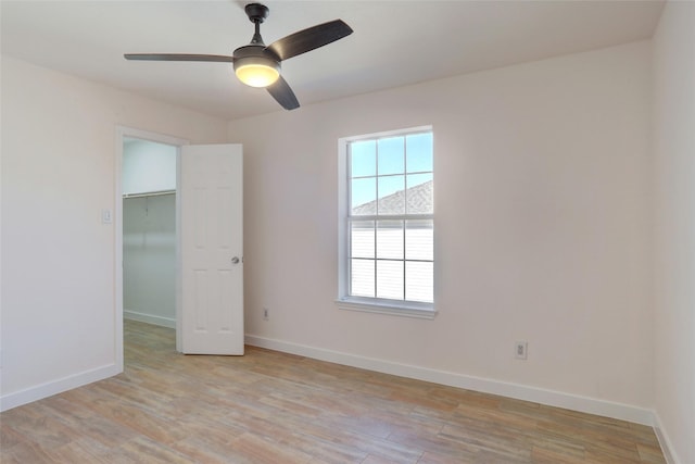 unfurnished bedroom with ceiling fan, a closet, light hardwood / wood-style flooring, and a walk in closet