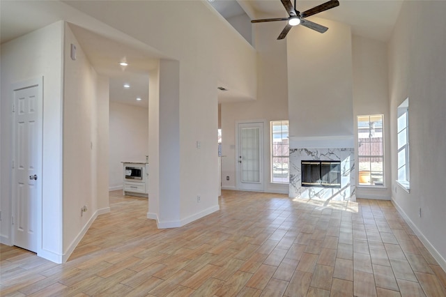 unfurnished living room featuring high vaulted ceiling, ceiling fan, and a fireplace