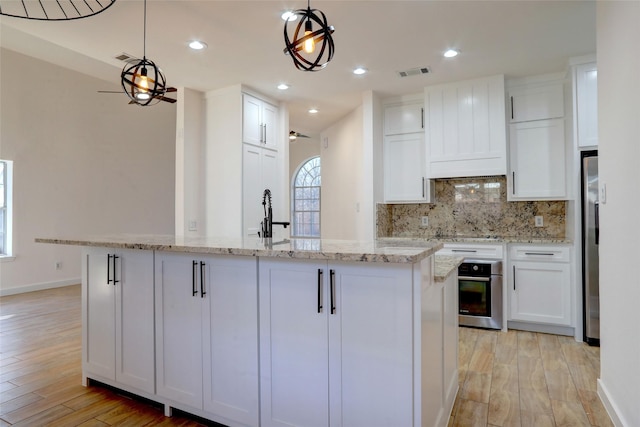 kitchen with decorative light fixtures, white cabinets, and stainless steel appliances