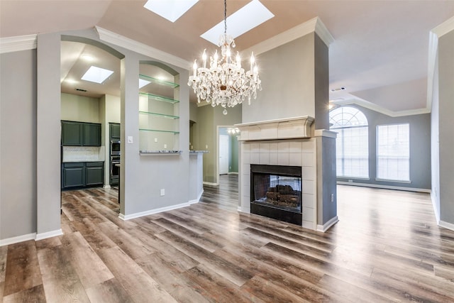 unfurnished living room with a tiled fireplace, hardwood / wood-style flooring, and lofted ceiling with skylight