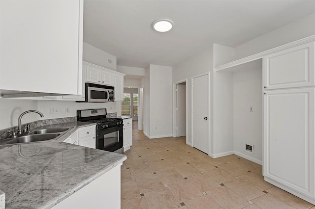 kitchen featuring sink, black gas stove, white cabinets, and light stone countertops