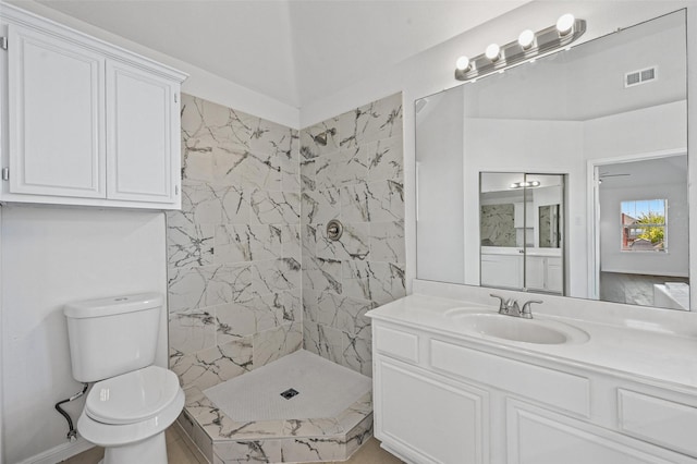 bathroom featuring tiled shower, vanity, and toilet