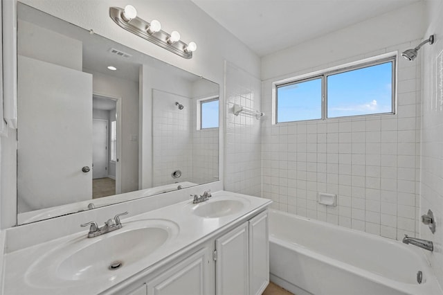 bathroom with tiled shower / bath combo and vanity