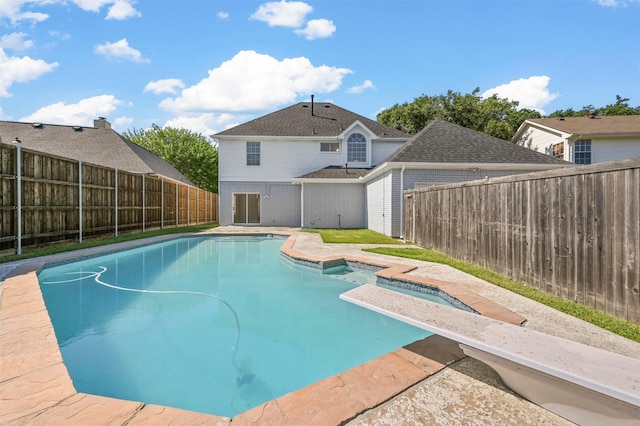 view of swimming pool with a diving board and a jacuzzi