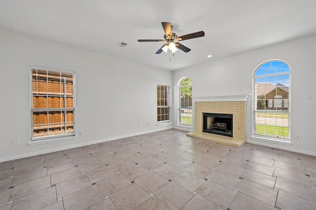 unfurnished living room with ceiling fan, a fireplace, and light tile patterned flooring