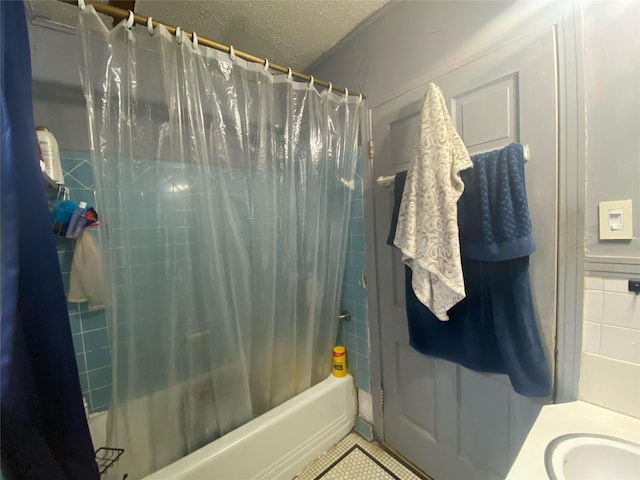 bathroom with tile patterned flooring, sink, a textured ceiling, and shower / bath combo with shower curtain