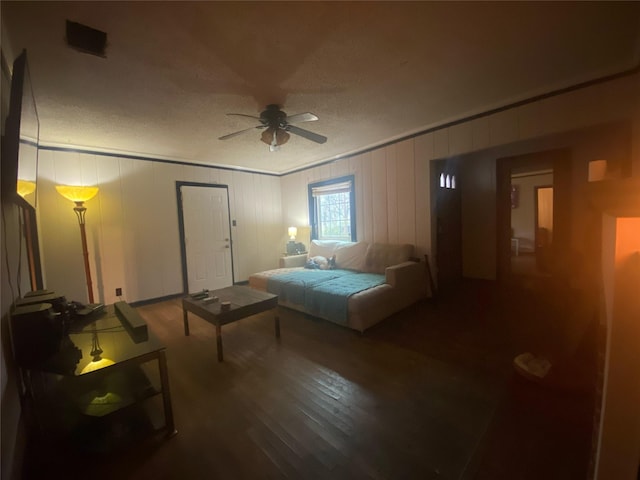 bedroom featuring a textured ceiling, wood-type flooring, ceiling fan, and wood walls