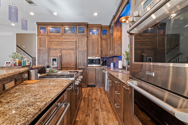 kitchen with hanging light fixtures, stainless steel double oven, and light stone counters