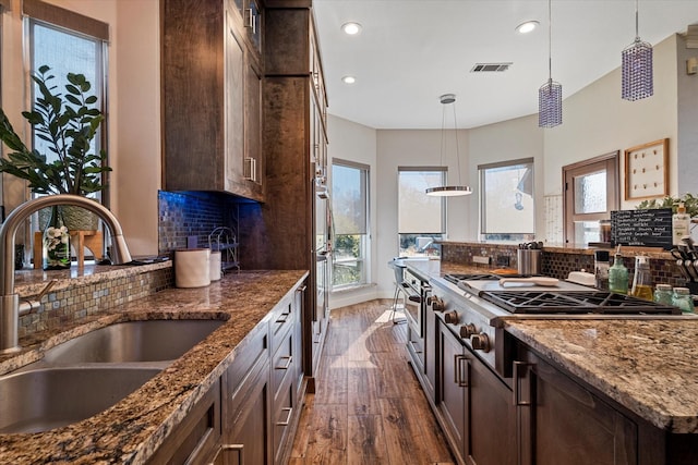 kitchen featuring hanging light fixtures, visible vents, dark stone counters, and a sink