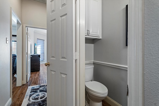 bathroom with baseboards, a textured wall, toilet, and wood finished floors