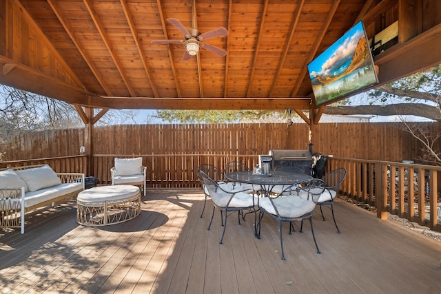 wooden terrace featuring a ceiling fan, outdoor dining space, fence, and a gazebo