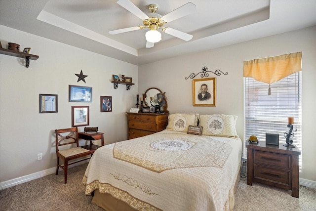 carpeted bedroom with a raised ceiling and ceiling fan