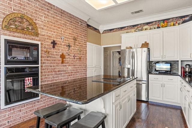 kitchen with dark stone countertops, a breakfast bar area, black appliances, and white cabinets