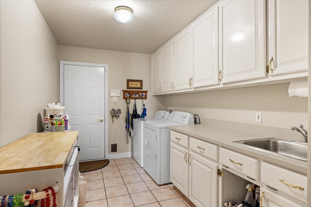 washroom featuring light tile patterned flooring, separate washer and dryer, sink, cabinets, and a textured ceiling