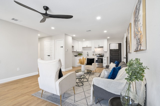 living room with ceiling fan, sink, and light hardwood / wood-style flooring