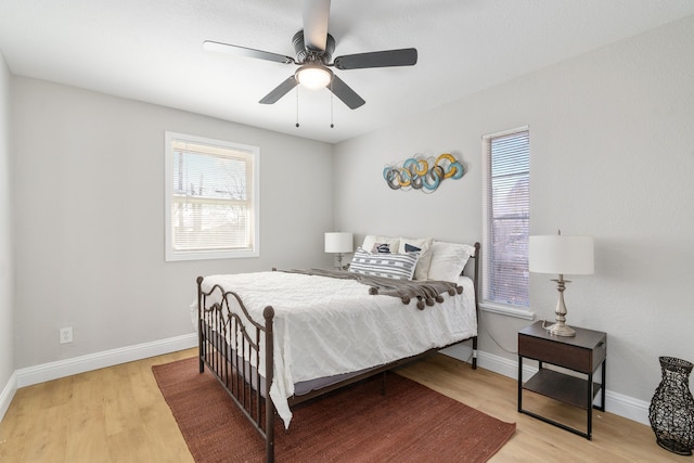 bedroom featuring ceiling fan, wood-type flooring, and multiple windows