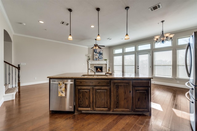 kitchen featuring sink, stainless steel appliances, dark brown cabinets, and an island with sink