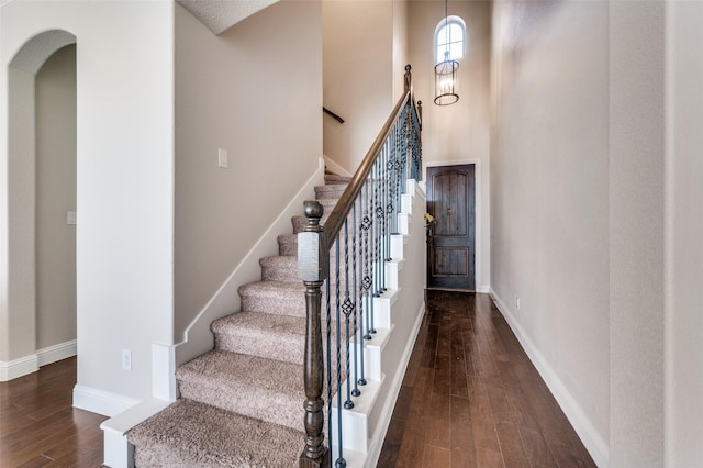 staircase with wood-type flooring and a high ceiling