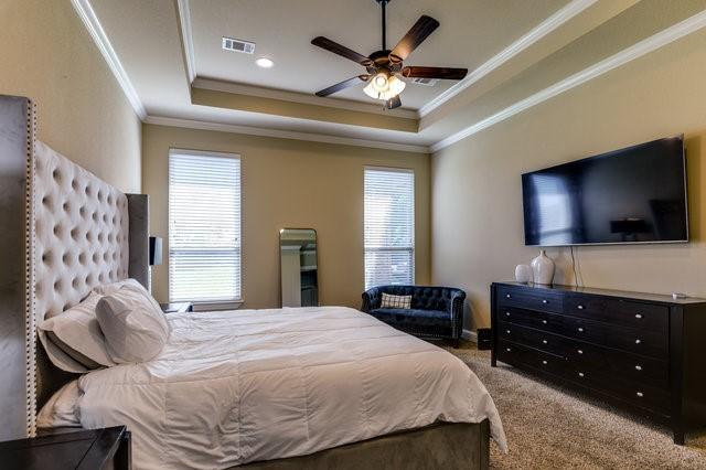 bedroom with ceiling fan, carpet, crown molding, and a tray ceiling