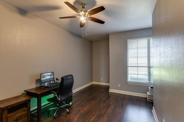 unfurnished office with ceiling fan and dark wood-type flooring