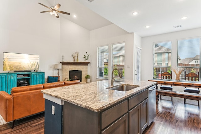 kitchen with stainless steel dishwasher, sink, dark brown cabinetry, an island with sink, and plenty of natural light