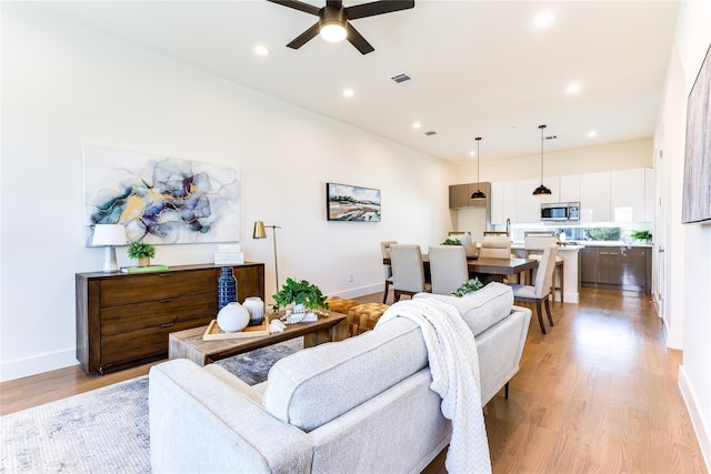 living room featuring ceiling fan and light hardwood / wood-style flooring