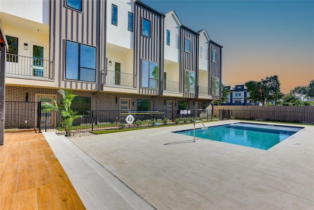 pool at dusk featuring a patio