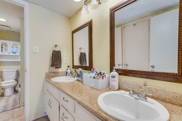 bathroom with a textured ceiling, tile patterned floors, vanity, and toilet