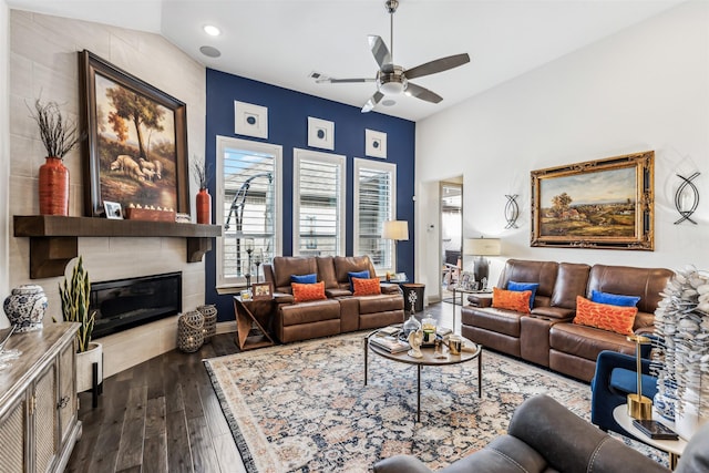 living room featuring ceiling fan, a tile fireplace, and dark hardwood / wood-style flooring