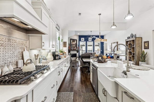 kitchen featuring custom exhaust hood, appliances with stainless steel finishes, white cabinets, decorative light fixtures, and backsplash