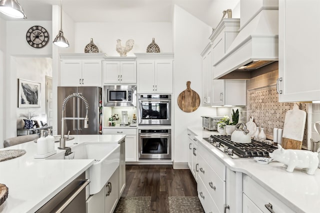 kitchen featuring white cabinetry, stainless steel appliances, custom range hood, and hanging light fixtures