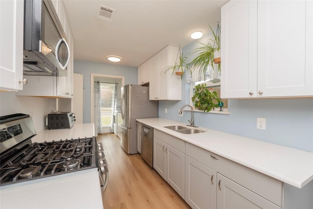 kitchen featuring sink, light hardwood / wood-style floors, white cabinetry, and appliances with stainless steel finishes