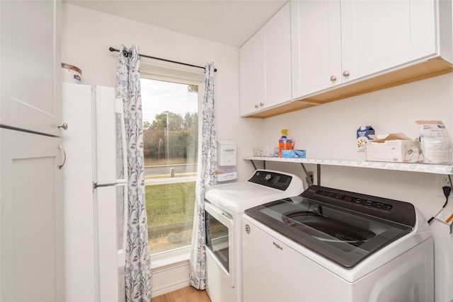 clothes washing area featuring light hardwood / wood-style floors, cabinets, and independent washer and dryer