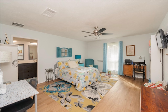 bedroom with light wood-type flooring, ensuite bathroom, and ceiling fan